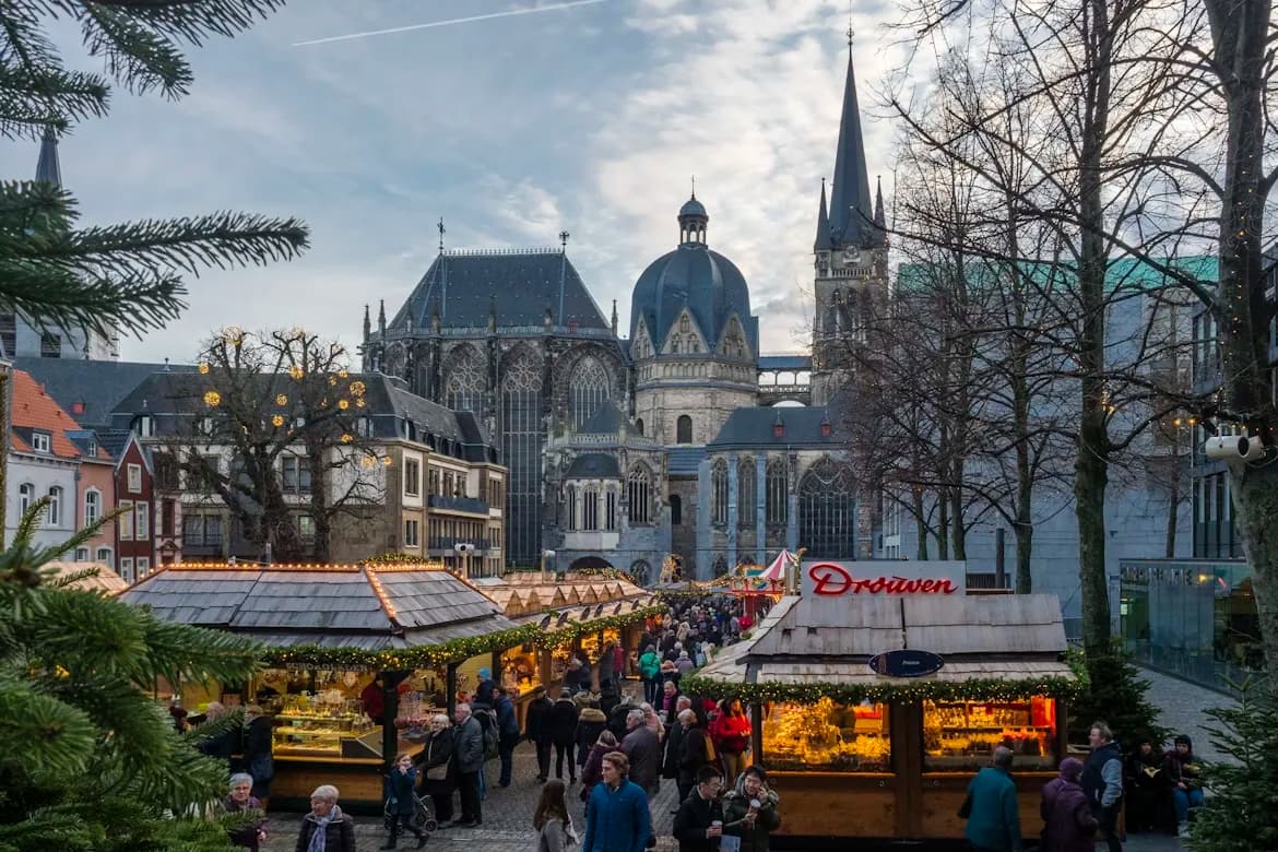 The Aachen Cathedral, a UNESCO World Heritage site, is surrounded by a festive Christmas market in the city's historic square.