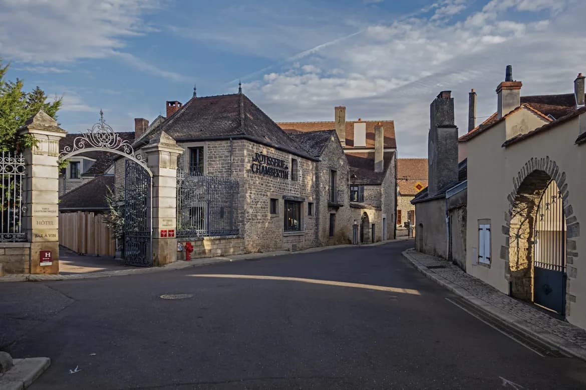 A charming, narrow street with traditional stone buildings and a large iron gate leads through the historic town.