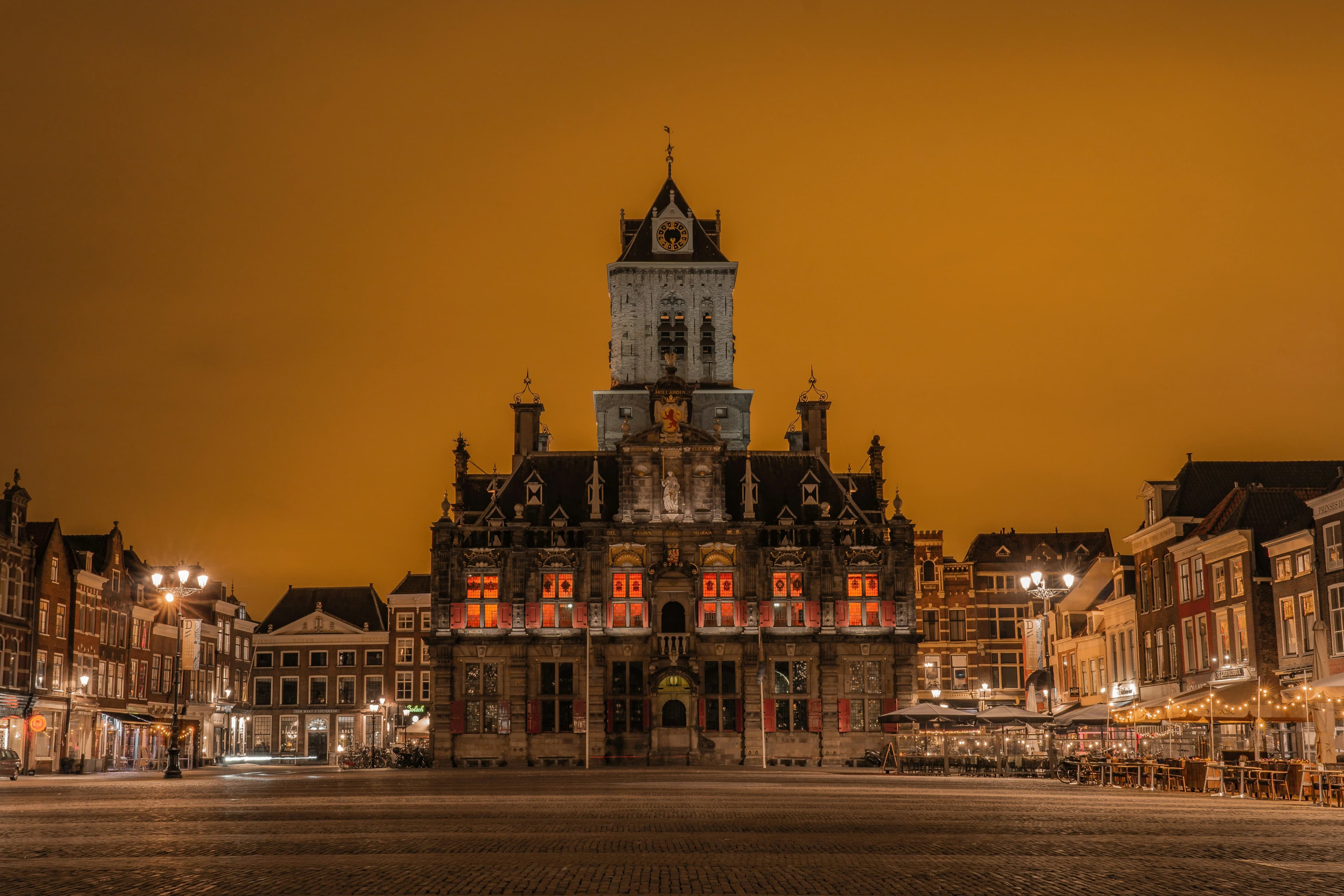 The historic City Hall of Delft glows warmly at night, highlighting its ornate Renaissance façade.