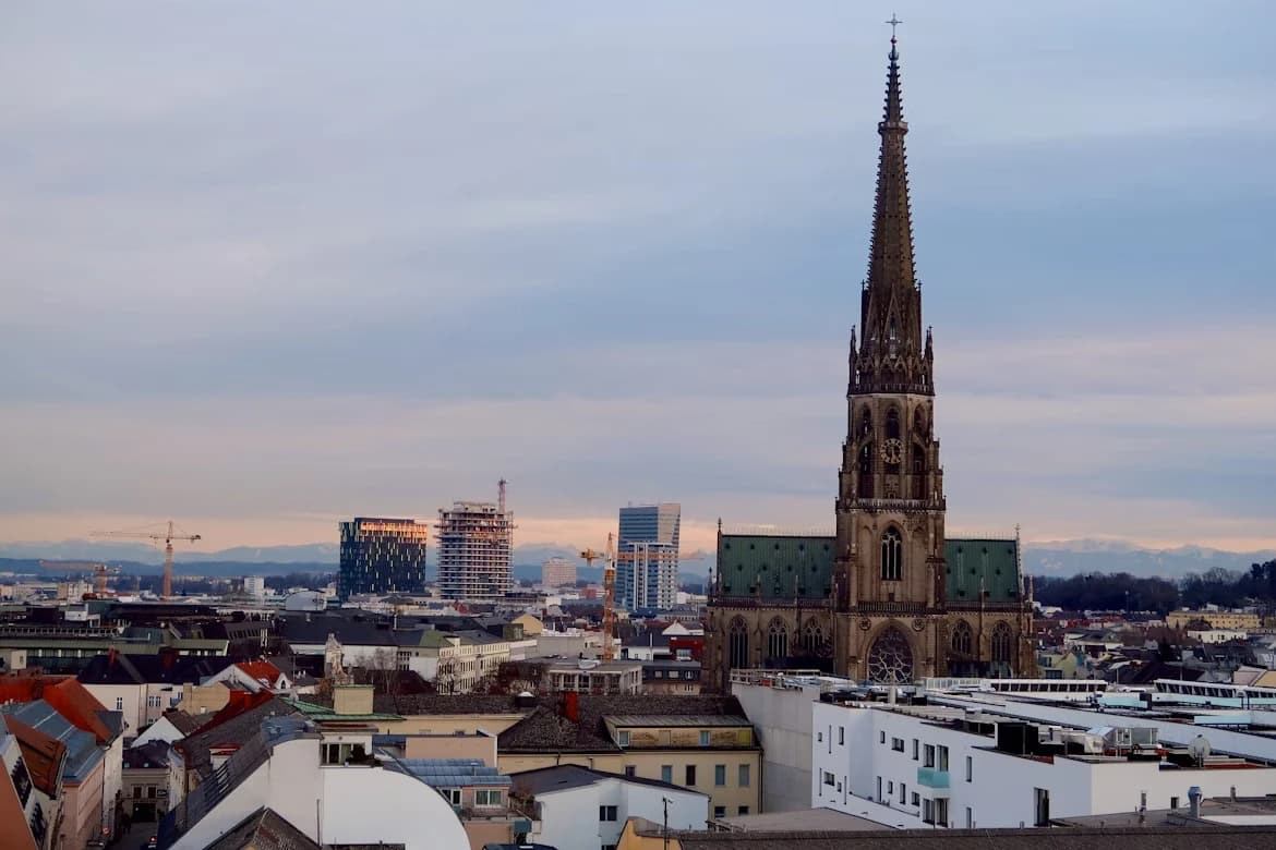 The towering steeple of St. Mary's Cathedral rises above the modern skyline of Linz.