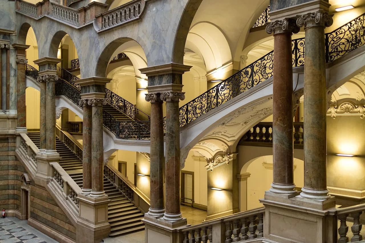The grand, majestic interior of a courthouse features a series of staircases, arches, and columns with intricate details.