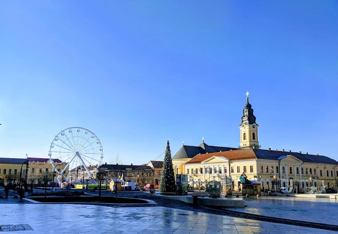 A large Ferris wheel and a decorated Christmas tree are the centerpiece of a city square with historic buildings.