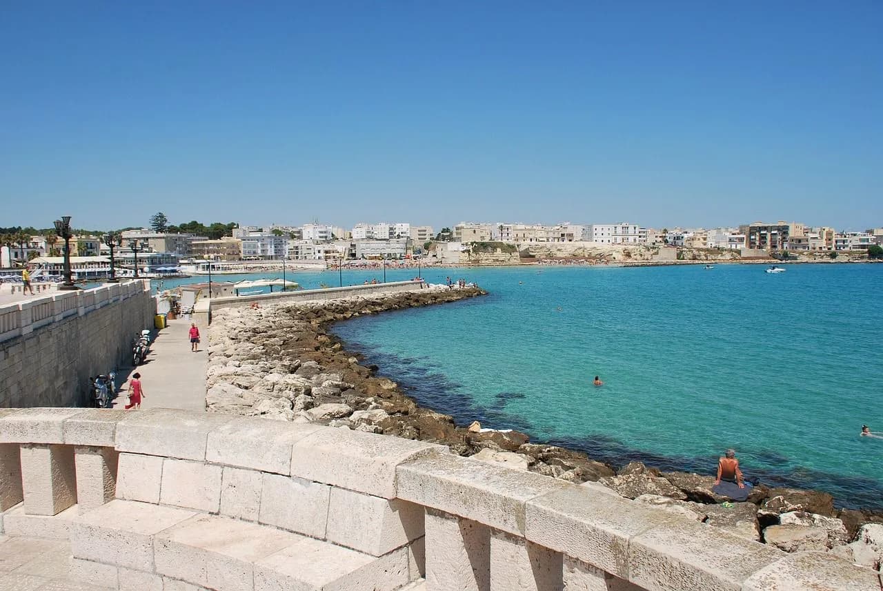 The historic Aragonese Castle of Otranto, a medieval fortress, is a beautiful backdrop to a wide, sandy beach.