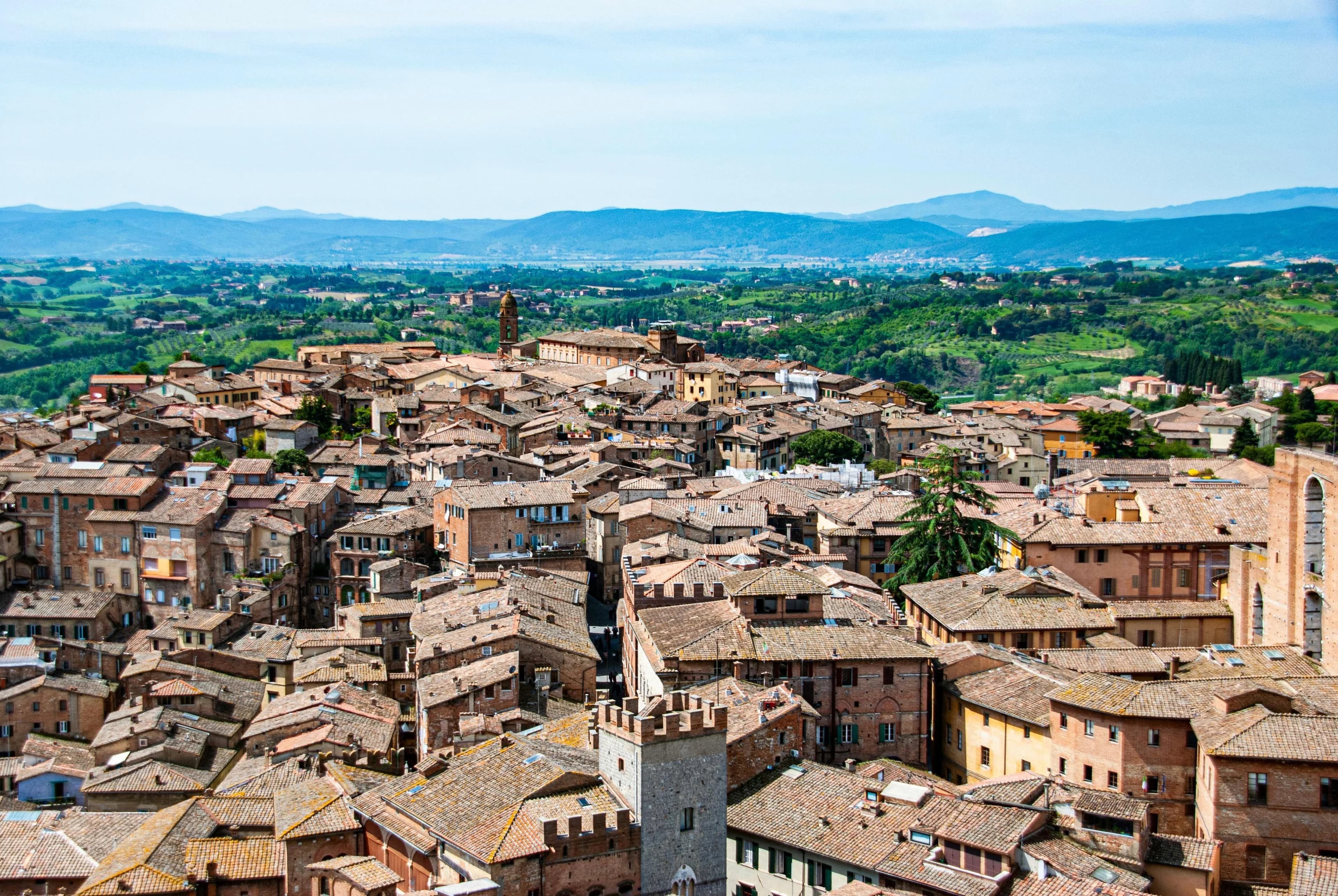 The magnificent Siena Cathedral, a masterpiece of Gothic architecture with intricate carvings and a marble facade, stands tall against a cloudy sky.