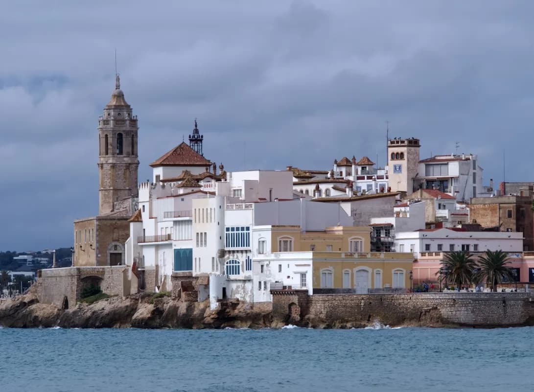 The historic church of Sant Bartomeu and Santa Tecla, with its tall bell tower, is a prominent landmark on the rocky coastline.