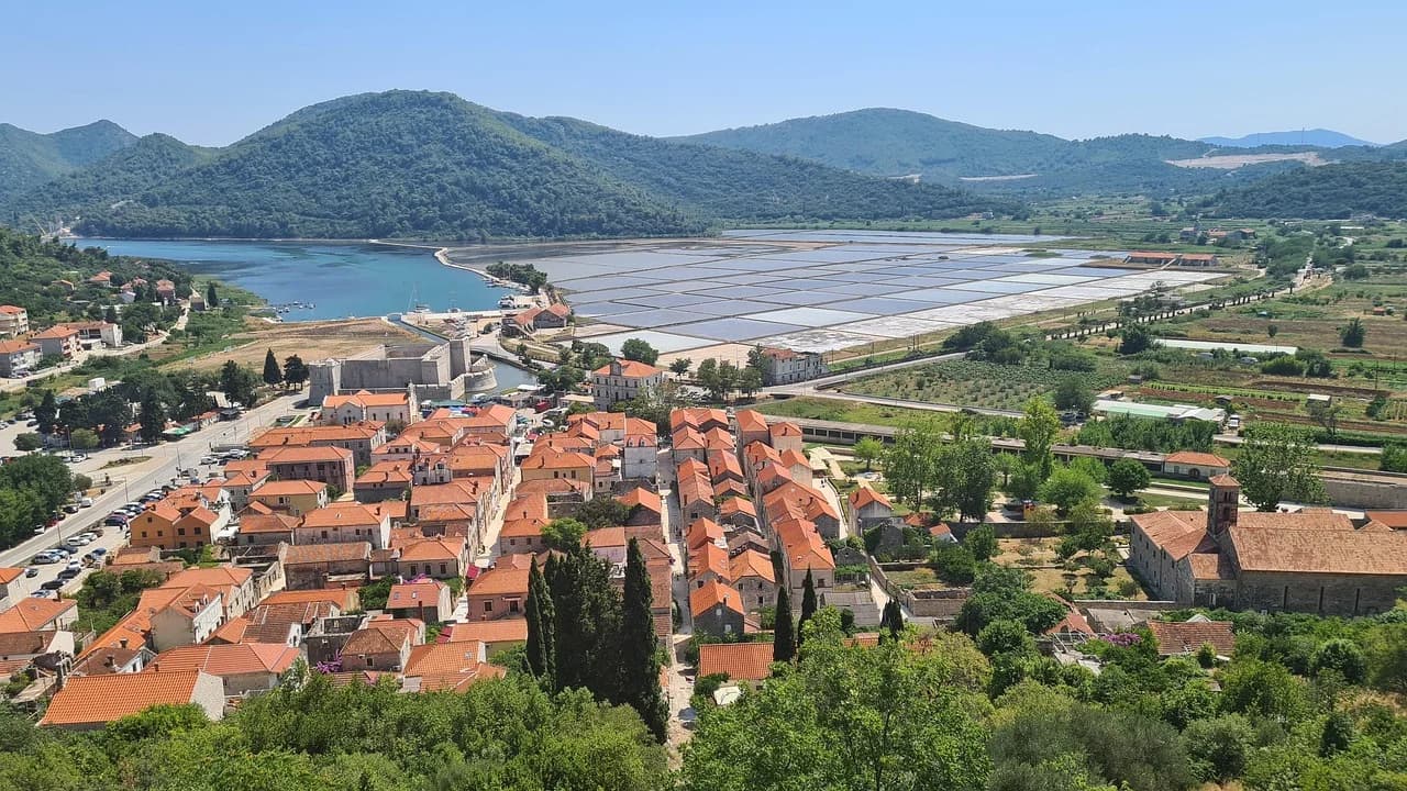The medieval town of Ston, with its red rooftops and a historic church, is nestled in a valley with a view of the famous salt pans.