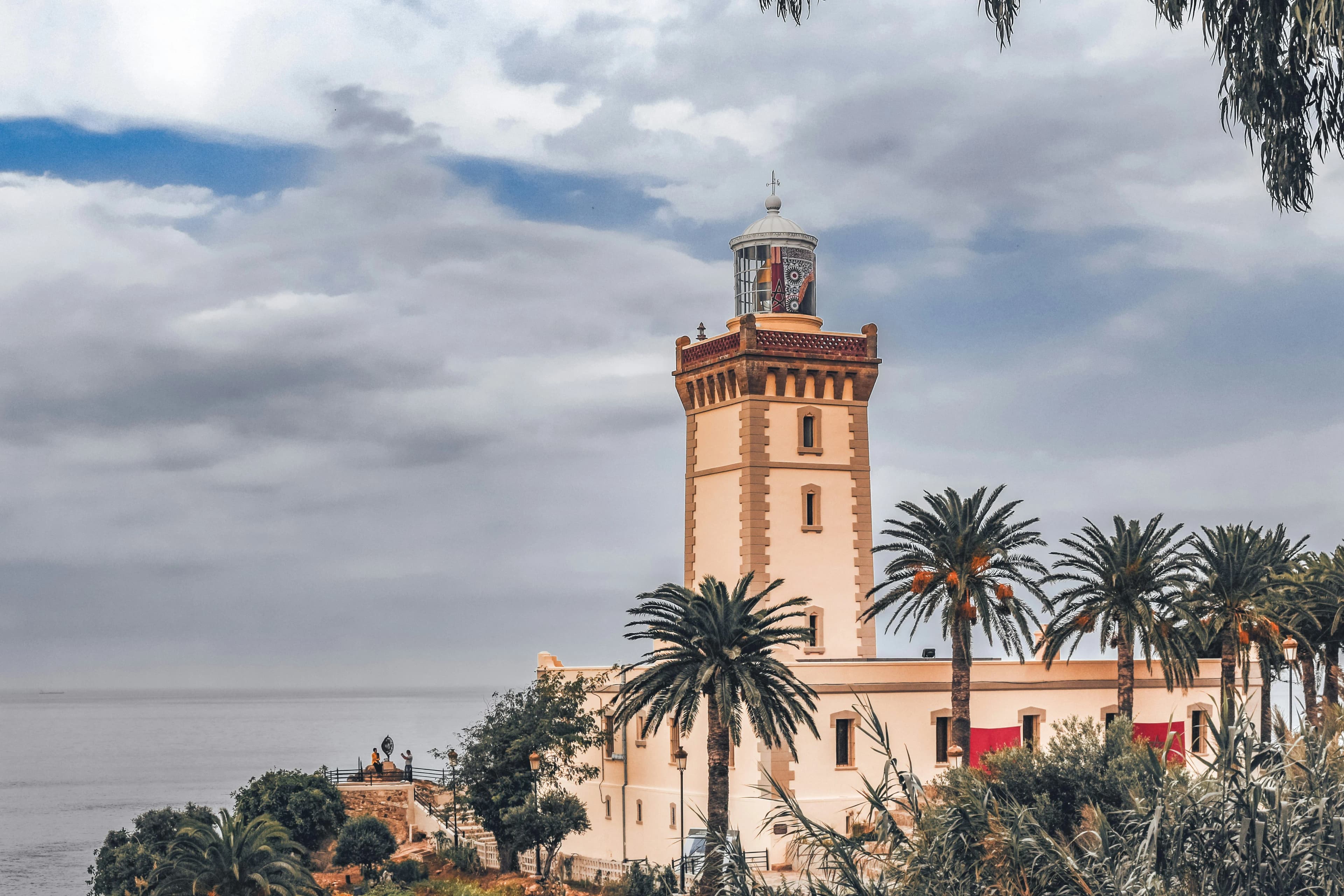 The Cap Spartel lighthouse, a historic landmark in Tangier, surrounded by palm trees and overlooking the ocean.