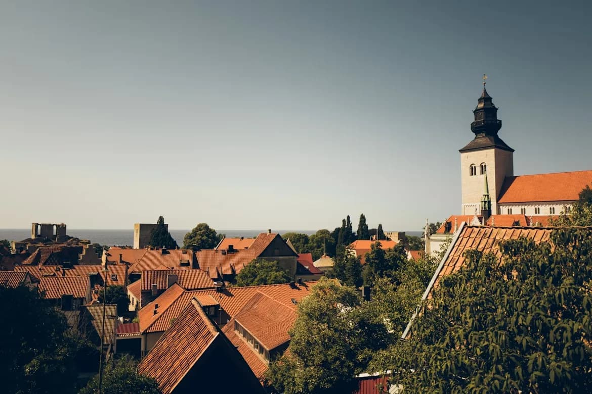 An elevated view captures the historic rooftops and a prominent church tower, with the calm Baltic Sea visible in the distance.