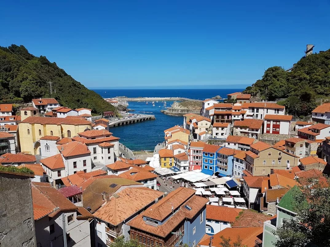 The picturesque village of Cudillero is nestled in a natural cove, with colorful buildings and a bustling port area.