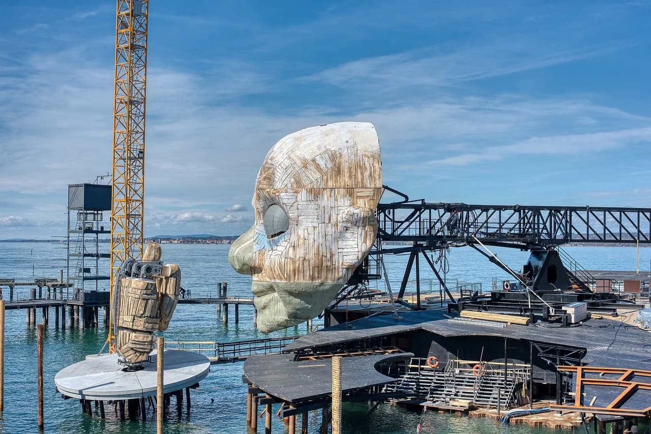 The massive stage and set of a theatrical production, including a large sculpted face, is set on a platform over Lake Constance.