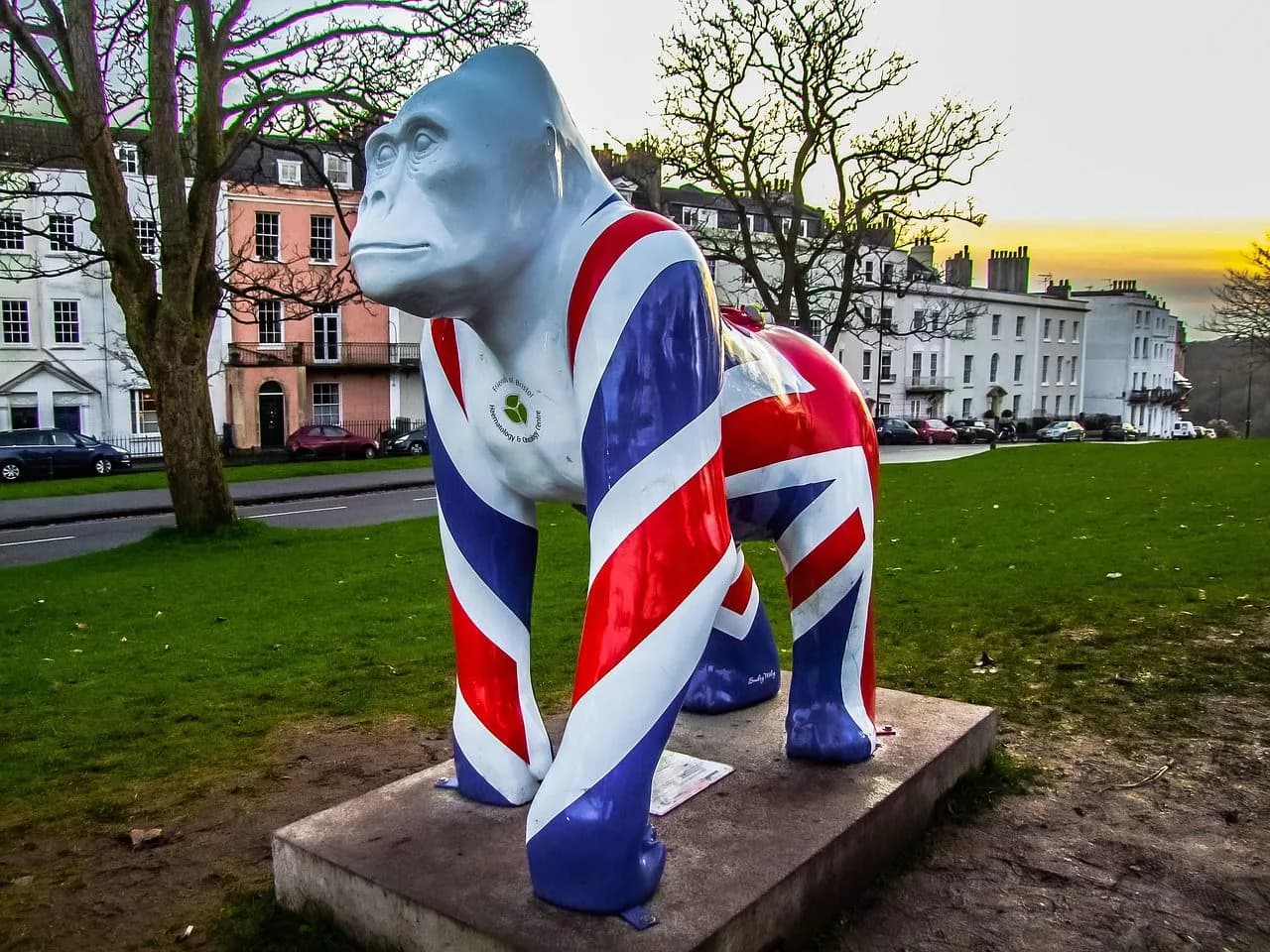 A gorilla statue painted with the Union Jack flag stands on a grassy park, a famous piece of street art.