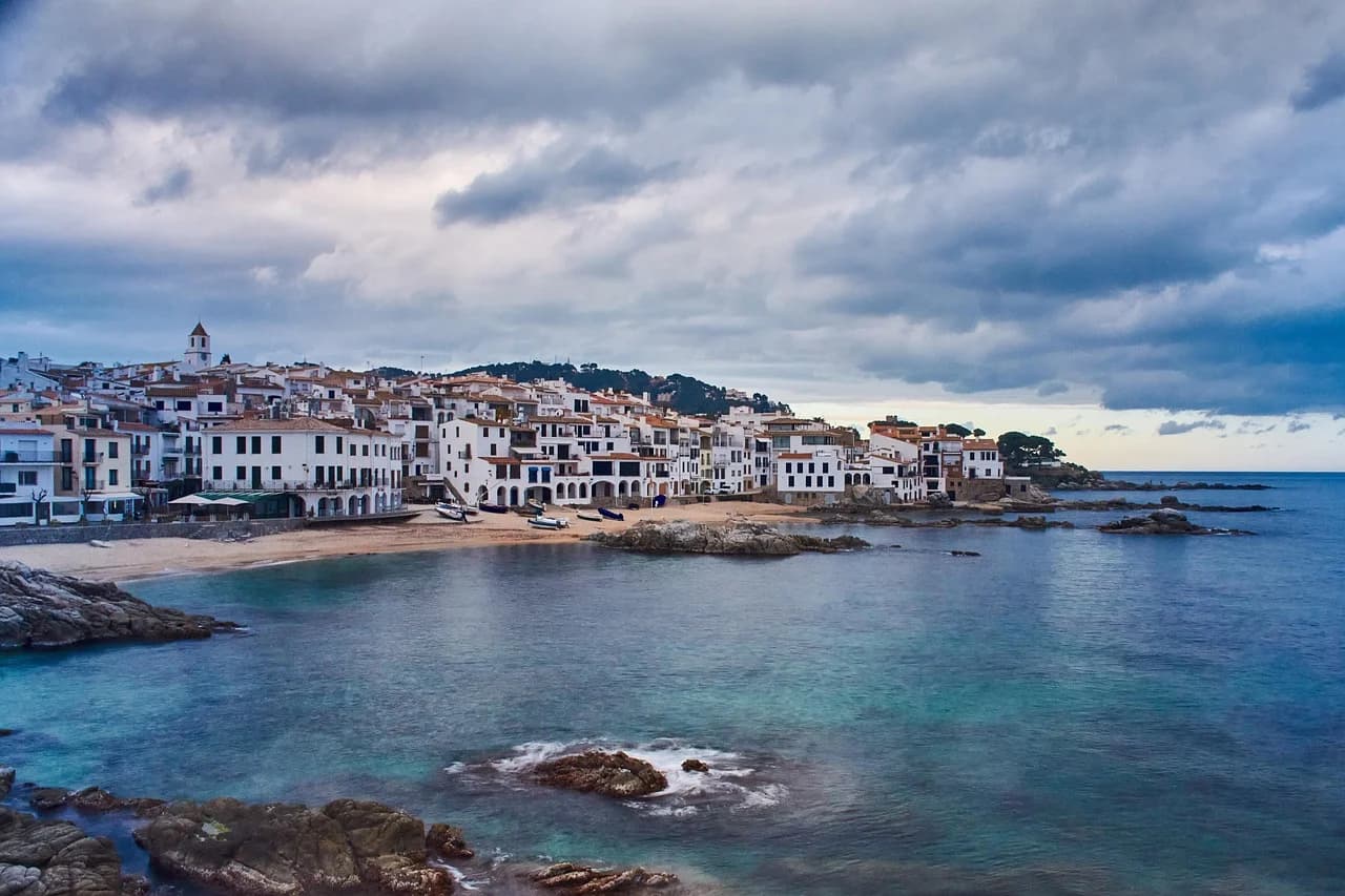 The small, traditional fishing village of Calella de Palafrugell is nestled on a rocky shoreline, with its white houses reflecting on the sea.
