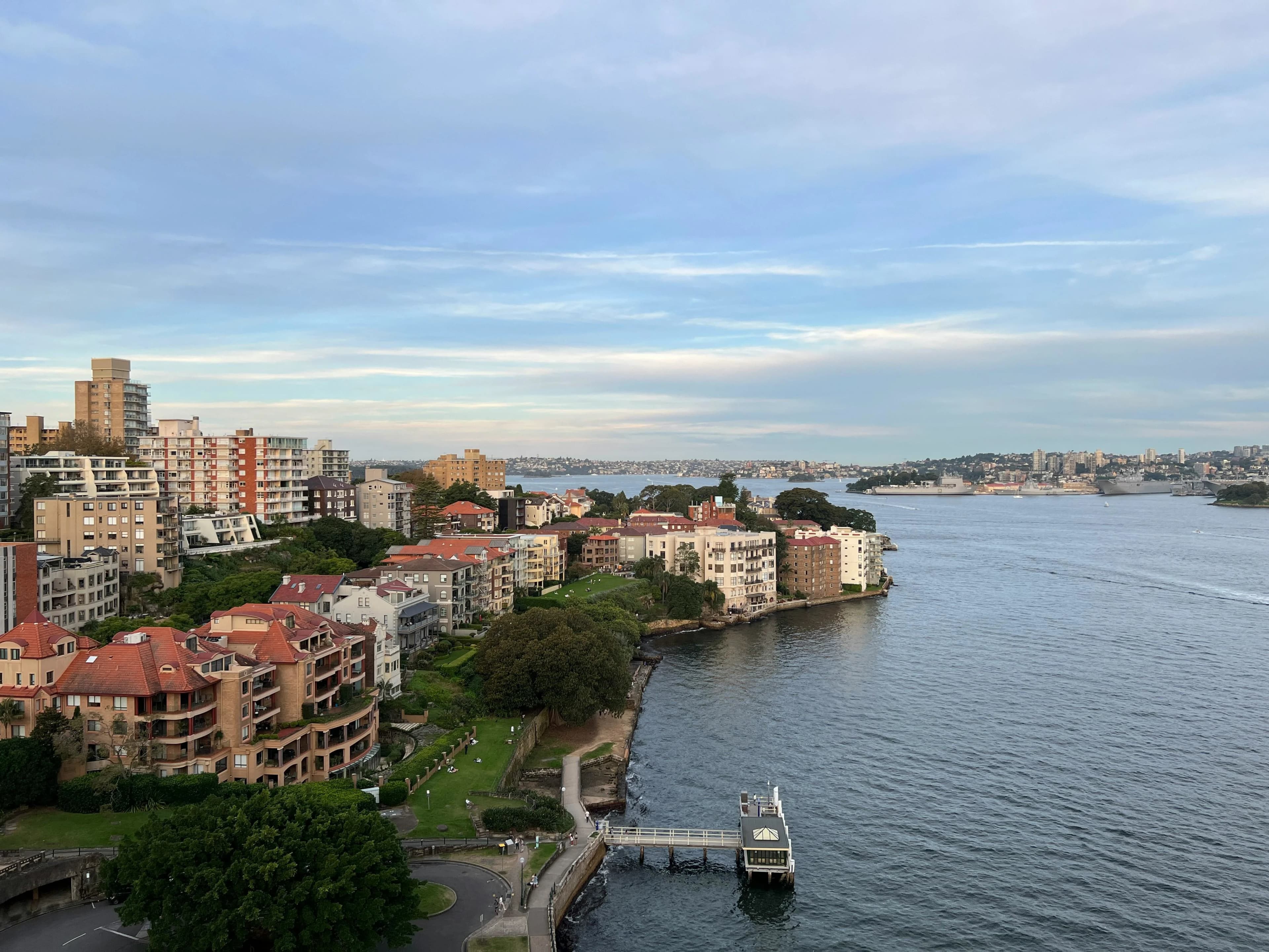 An aerial view captures the dramatic coastline and a residential area with traditional red-tiled roofs overlooking the bay.