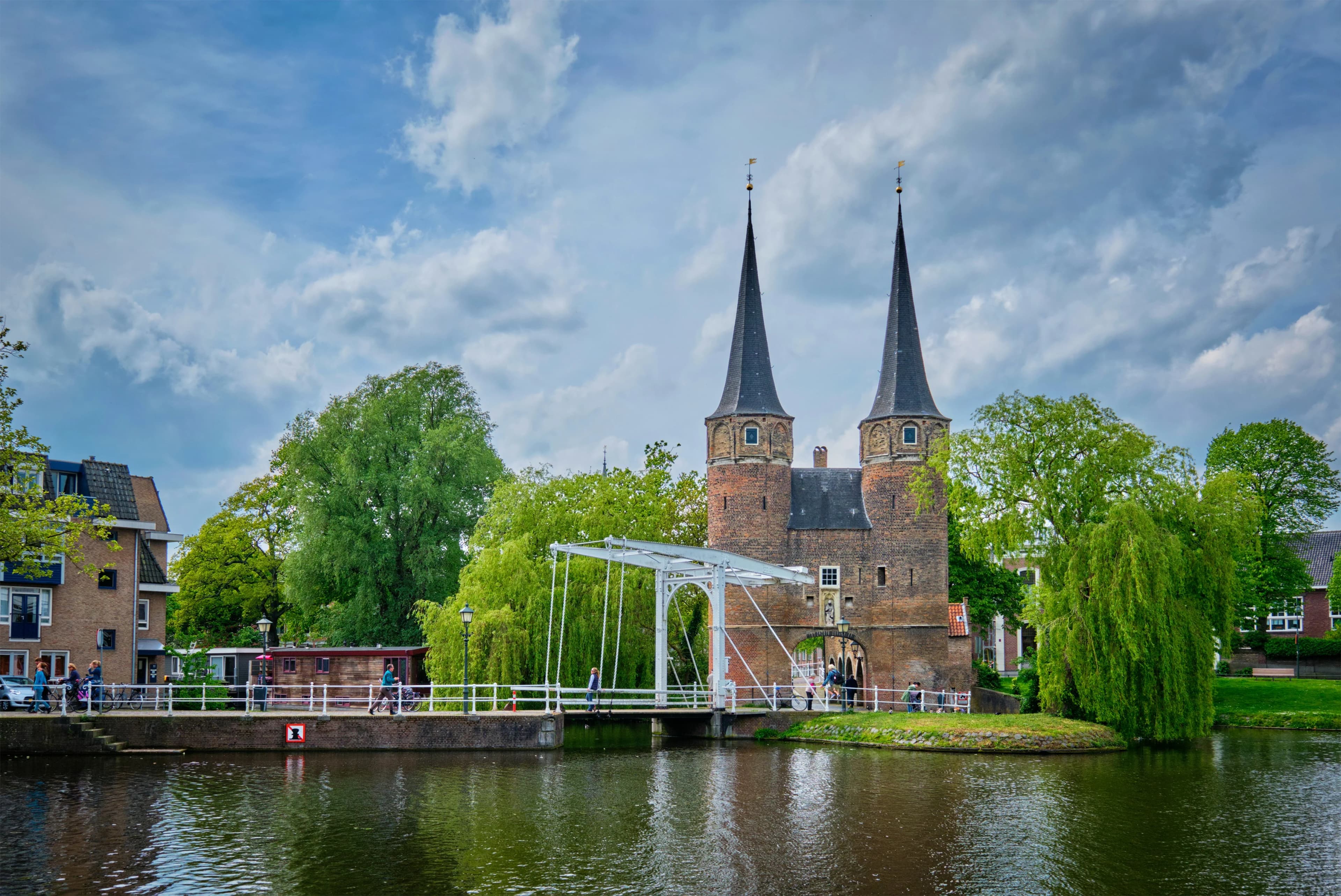 The Oostpoort, a historic city gate of Delft with twin spires and a drawbridge over a tranquil canal.