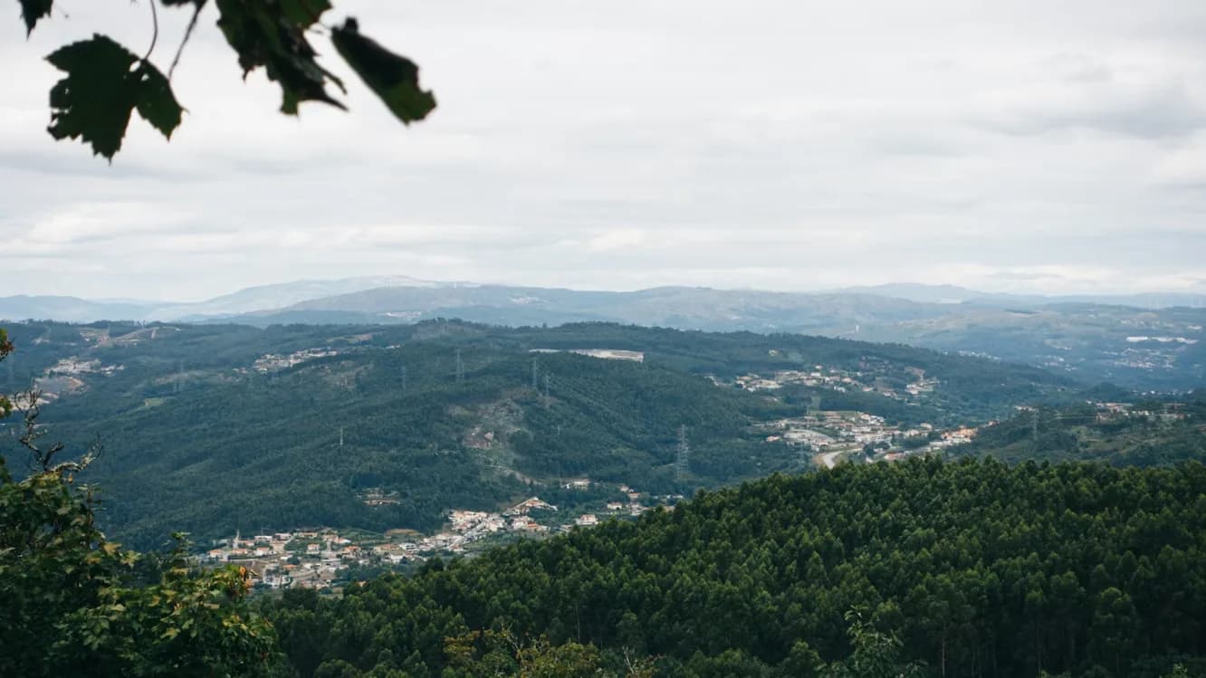 An aerial view captures the lush, green landscape of Guimarães, with small towns and rolling hills in the distance.