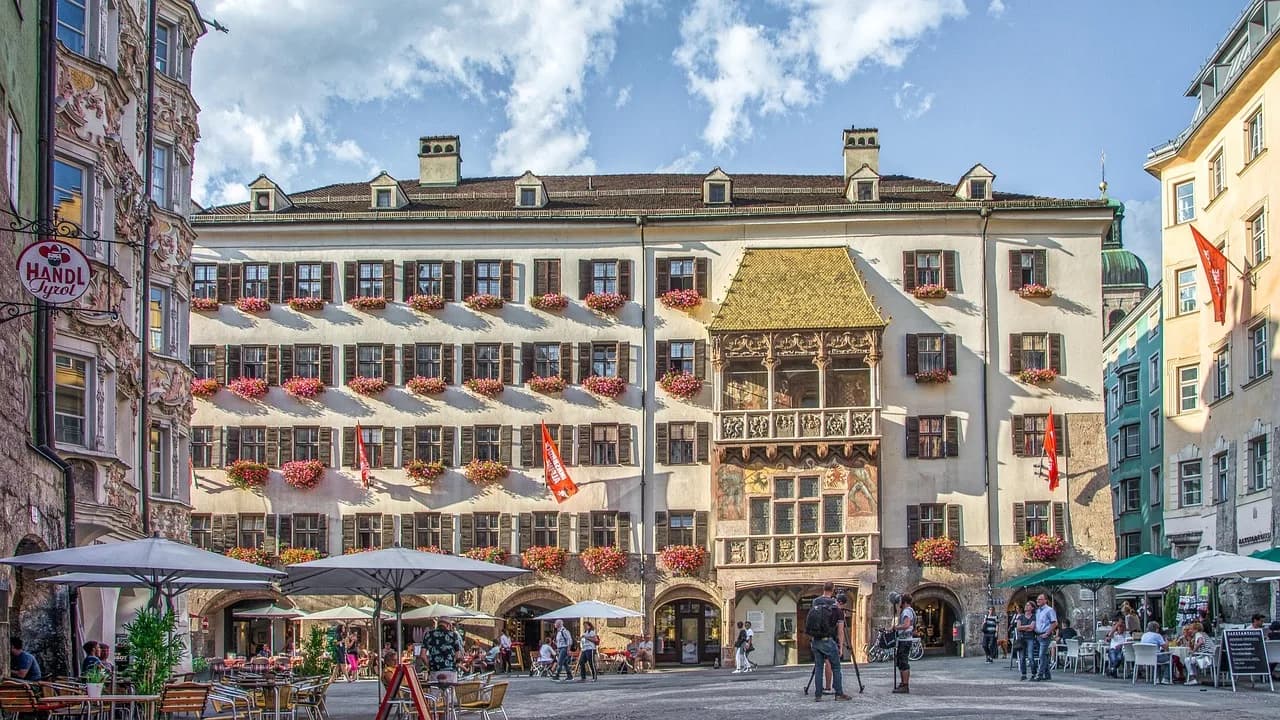 The famous Goldenes Dachl, or Golden Roof, with its ornate balcony and vibrant frescoes, is the centerpiece of a lively square.