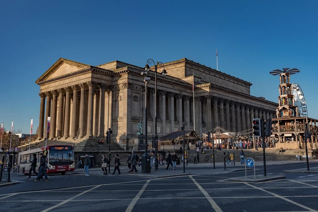 The neoclassical facade of St. George's Hall is beautifully illuminated, with a festive Christmas market and a Ferris wheel in the square.