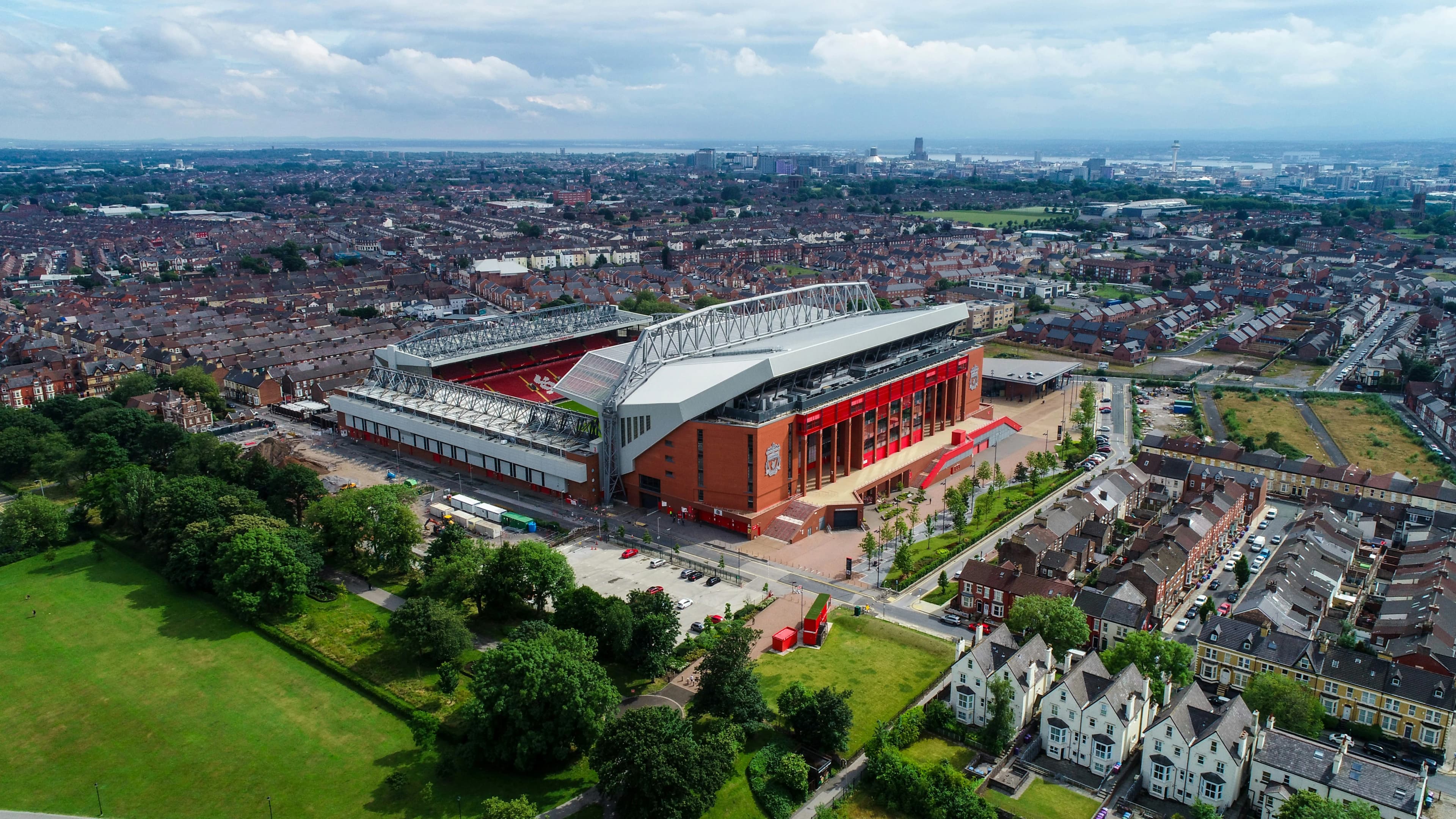 An aerial view captures the expansive Anfield stadium, home of the Liverpool Football Club, surrounded by residential areas.