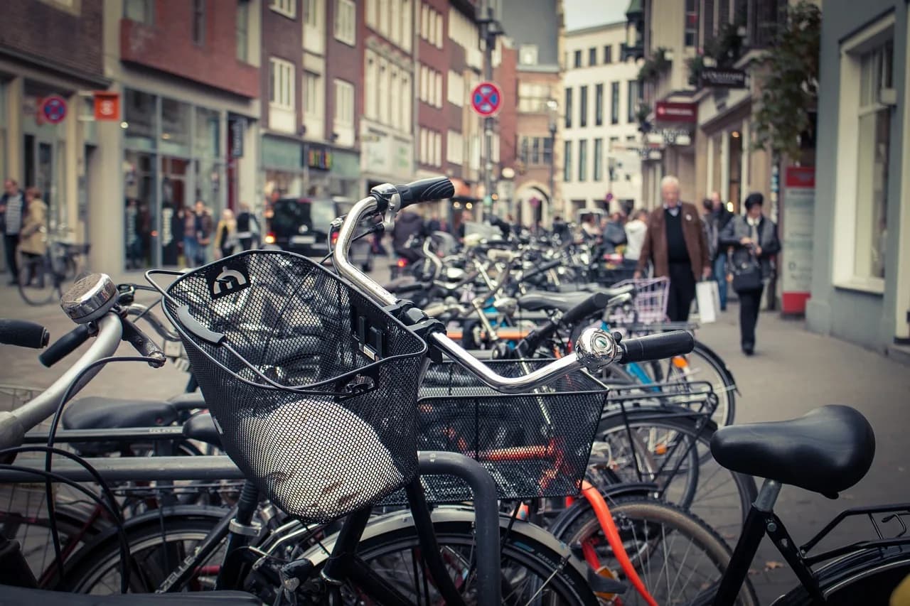 A historic street is filled with numerous bicycles, with people walking and shopping in the background.