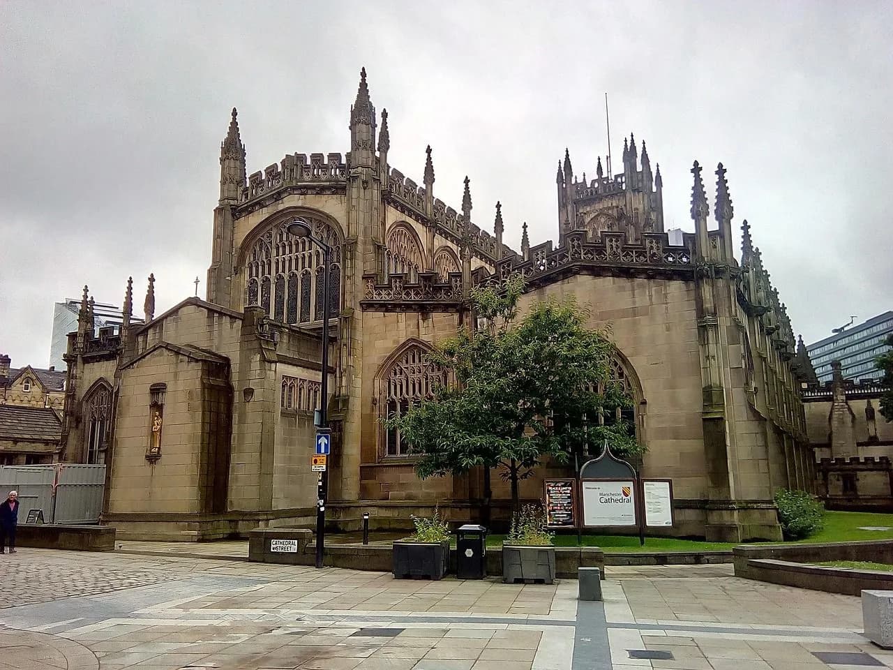 The magnificent Manchester Cathedral, a gothic masterpiece with intricate stonework, stands in a quiet city square.