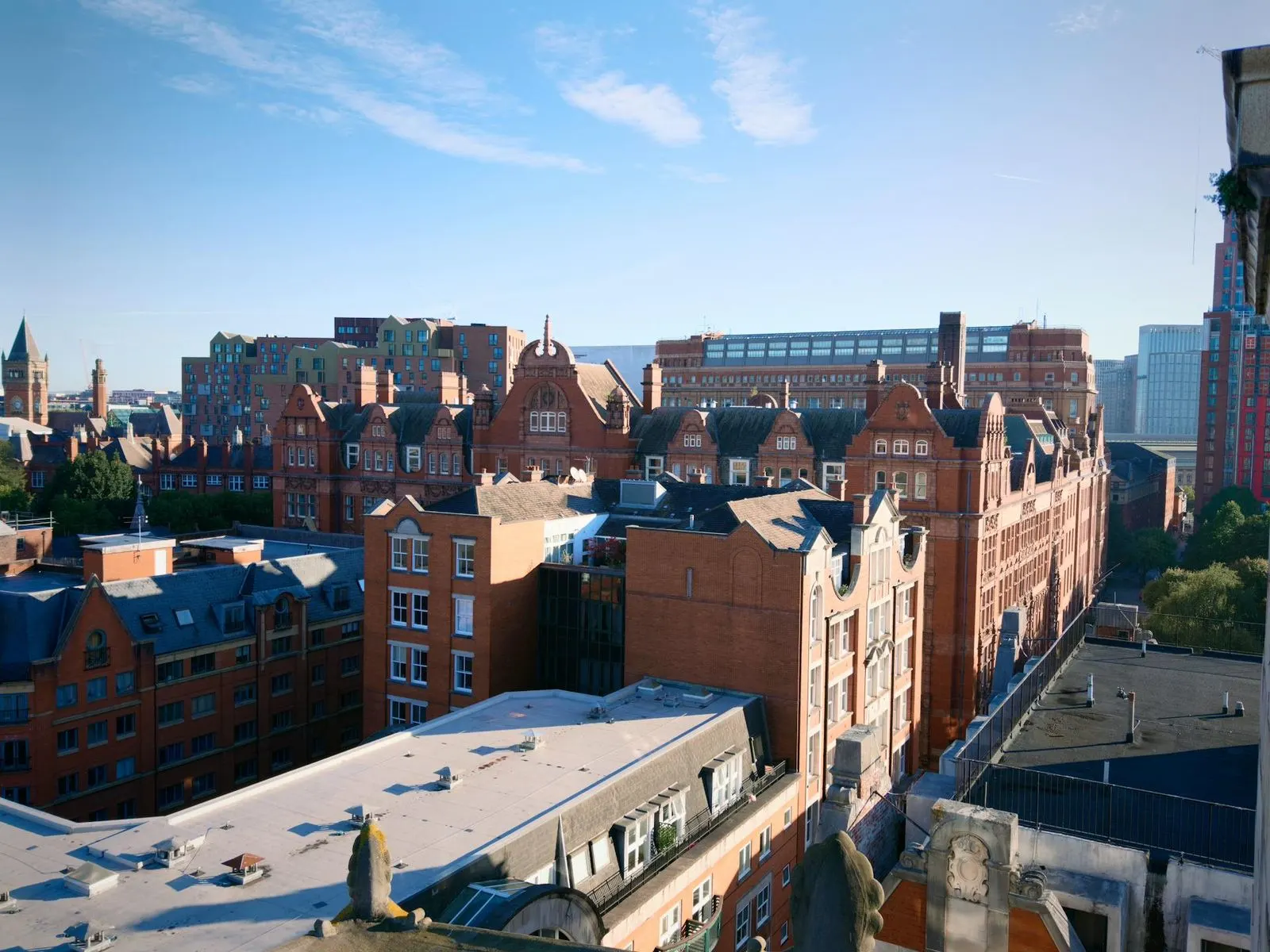 A high-angle view captures the red-brick facades of historic buildings in Manchester, with a mix of modern architecture in the background.