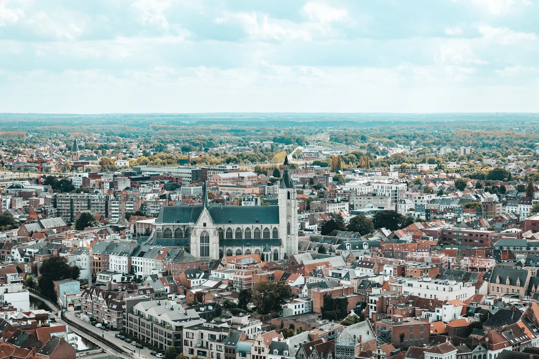 The magnificent St. Rumbold's Cathedral stands in the center of Mechelen, surrounded by the city's rooftops.