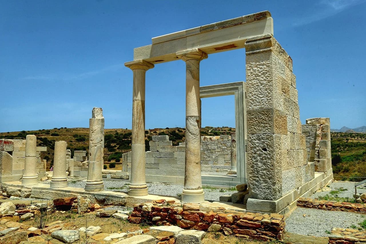 The ancient ruins of the Temple of Demeter stand on a hill, with a few columns and a large doorway.