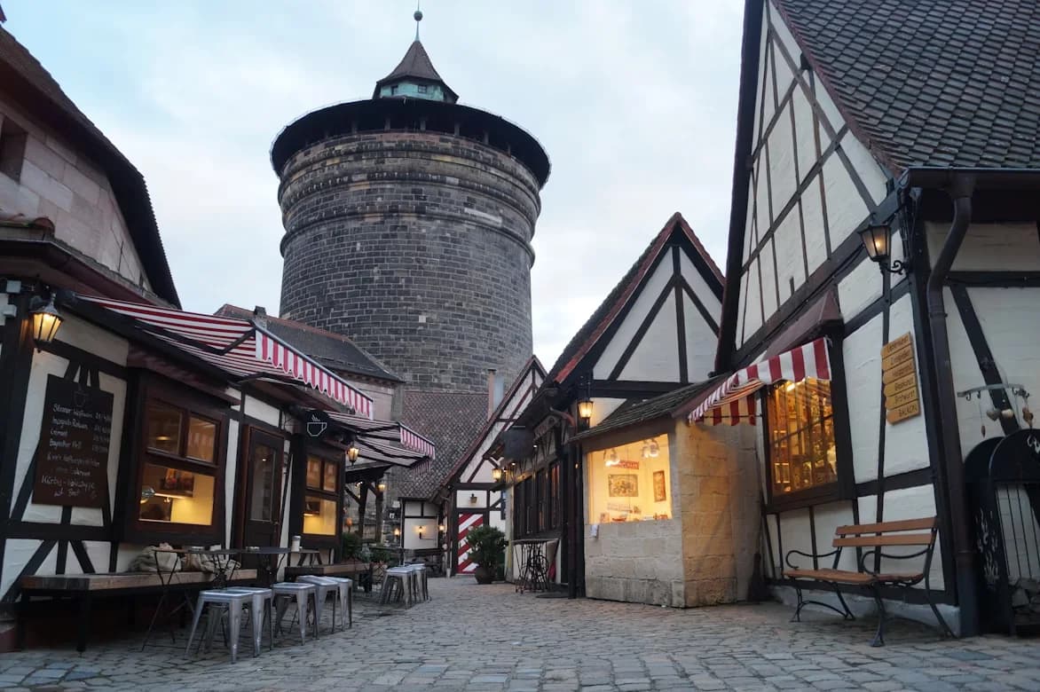 A cobblestone alleyway with half-timbered houses and a medieval tower creates a charming and historic scene.