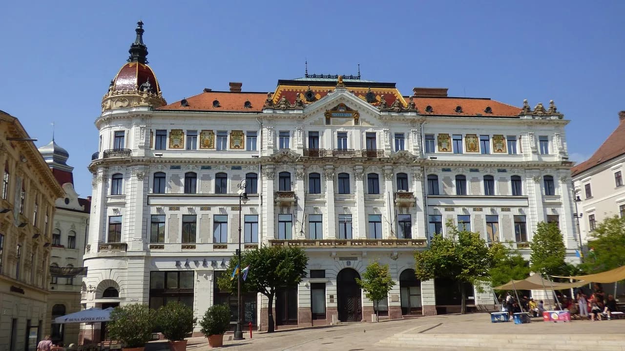The grand, ornate facade of the Széchenyi tér building is a highlight of a bustling square.