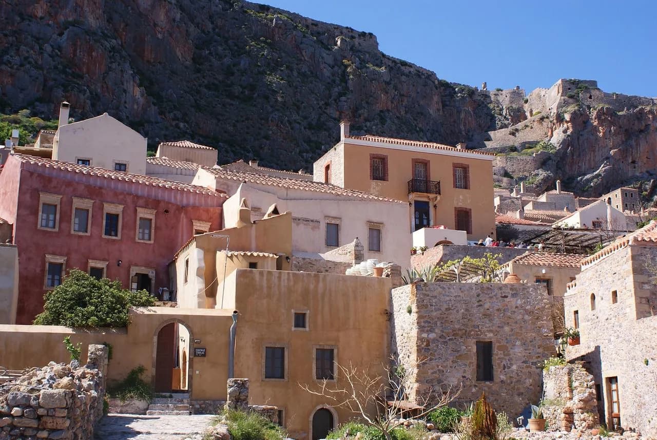 The historic, stone buildings of the medieval town of Monemvasia are built into a rocky cliffside.