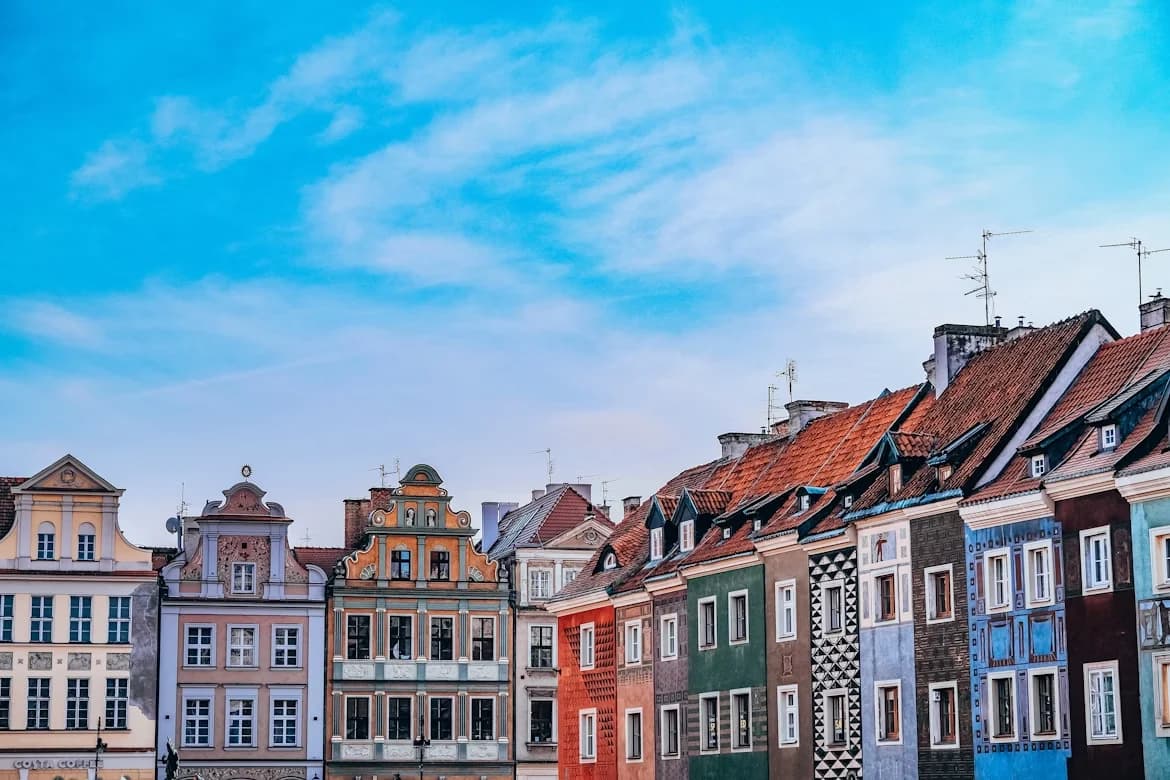 A row of colorful, historic gabled houses with unique facades lines a cobblestone street.