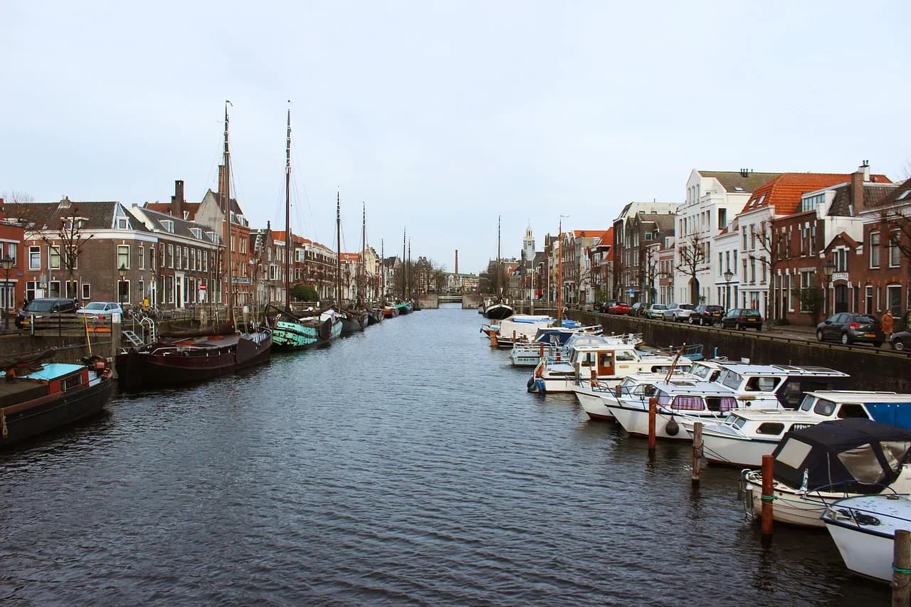A canal in Rotterdam is lined with traditional Dutch houses and numerous boats, creating a serene and picturesque scene.