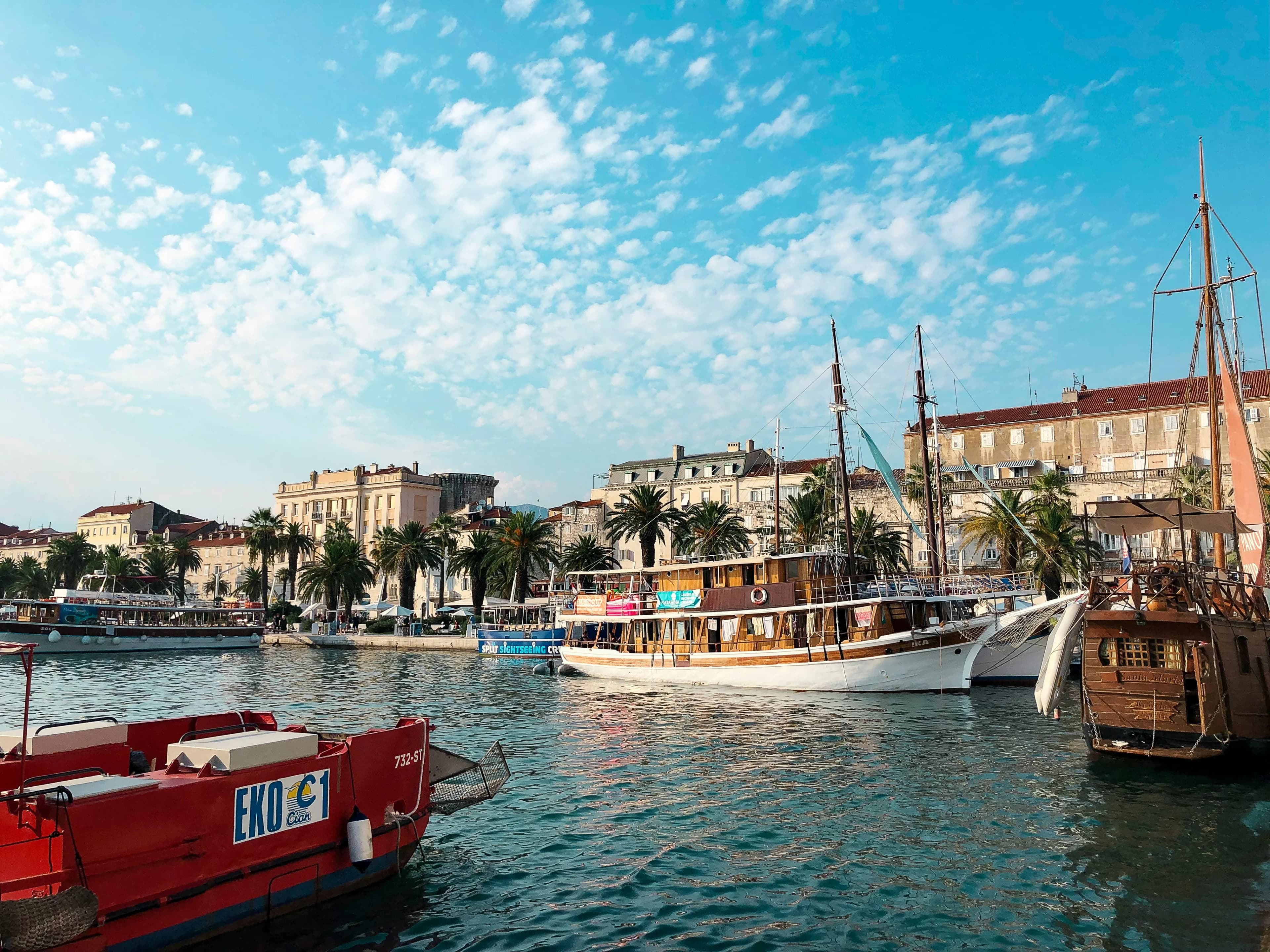 The bustling harbor of Split, with a variety of boats and ships docked along the promenade.