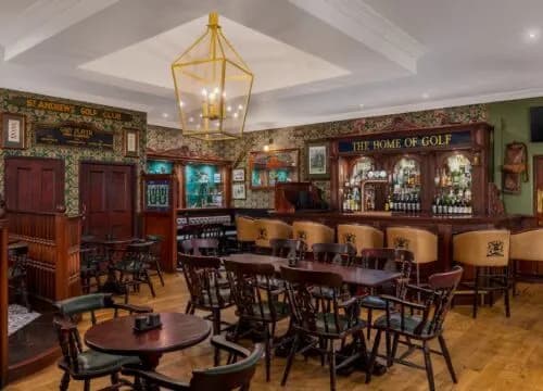 The cozy and elegant interior of a traditional Scottish pub, with wooden furniture and a bar filled with various liquors.