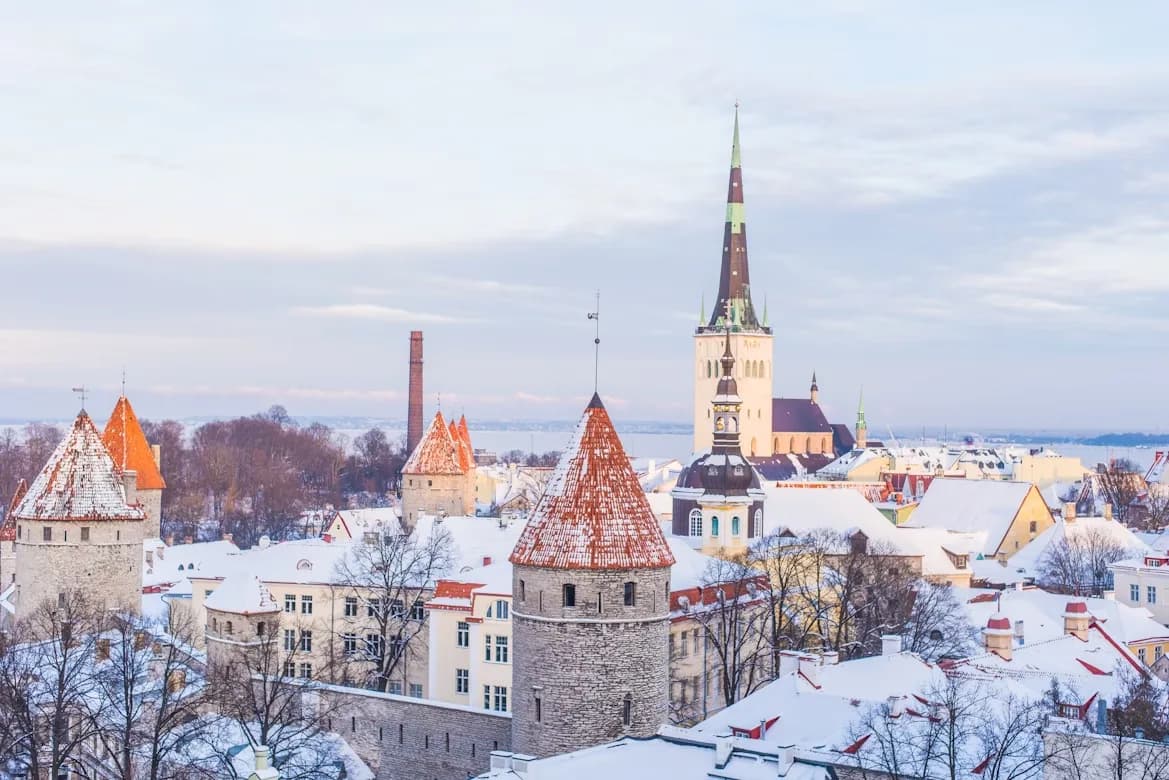 A quiet city street in Tallinn is lined with elegant, colorful buildings and is bordered by the medieval city walls.